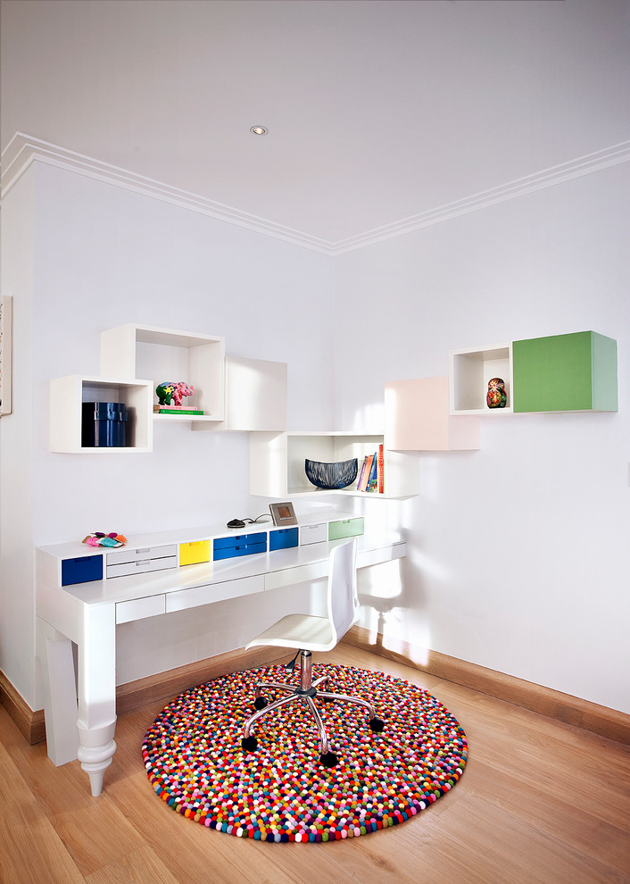 Contemporary study in London with white walls, light hardwood flooring and a freestanding desk.
