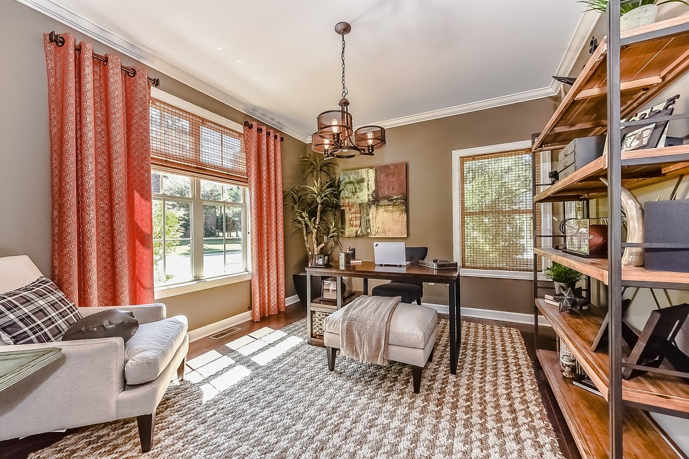This is an example of a medium sized classic study in Charlotte with brown walls, light hardwood flooring, no fireplace and a freestanding desk.