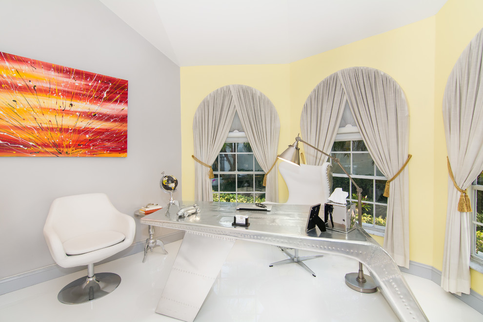 Klassisches Arbeitszimmer ohne Kamin mit Arbeitsplatz, gelber Wandfarbe, freistehendem Schreibtisch und weißem Boden in Miami