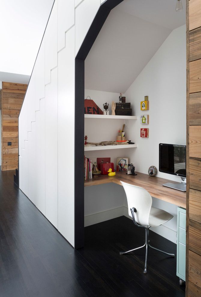 Trendy built-in desk dark wood floor study room photo in Austin with white walls