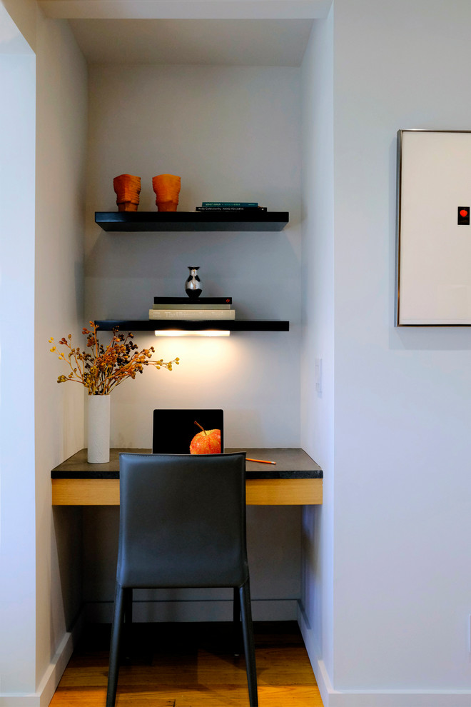 Diseño de despacho actual grande con paredes grises, suelo de madera clara, escritorio empotrado y suelo beige