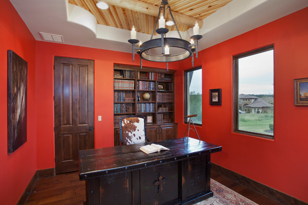 На фото: кабинет в стиле фьюжн с красными стенами, темным паркетным полом и отдельно стоящим рабочим столом с