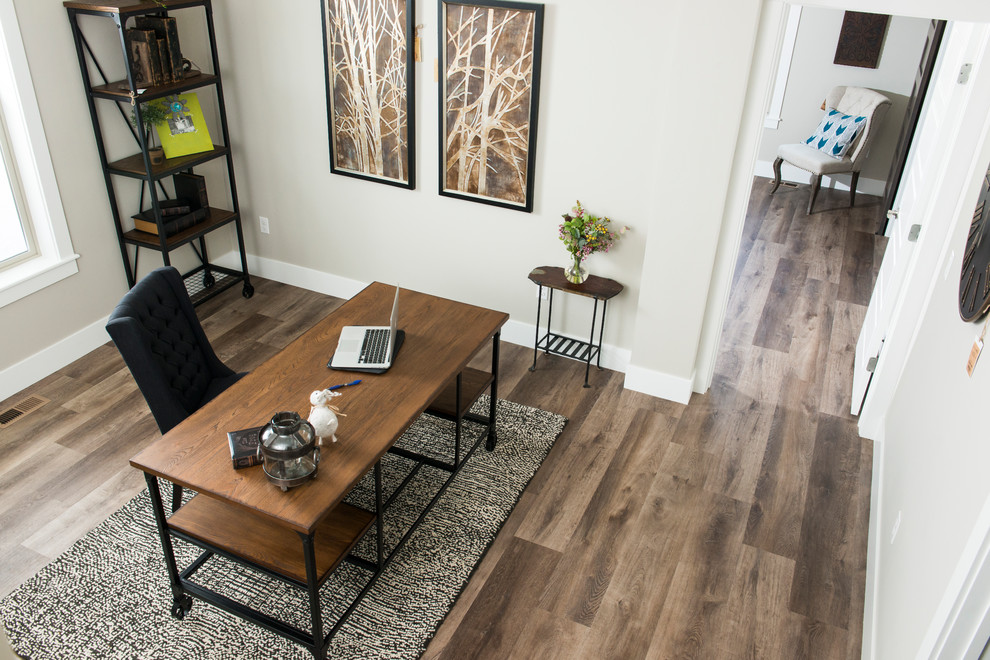 Modelo de despacho tradicional renovado pequeño sin chimenea con paredes grises, suelo de madera en tonos medios, escritorio independiente y suelo marrón