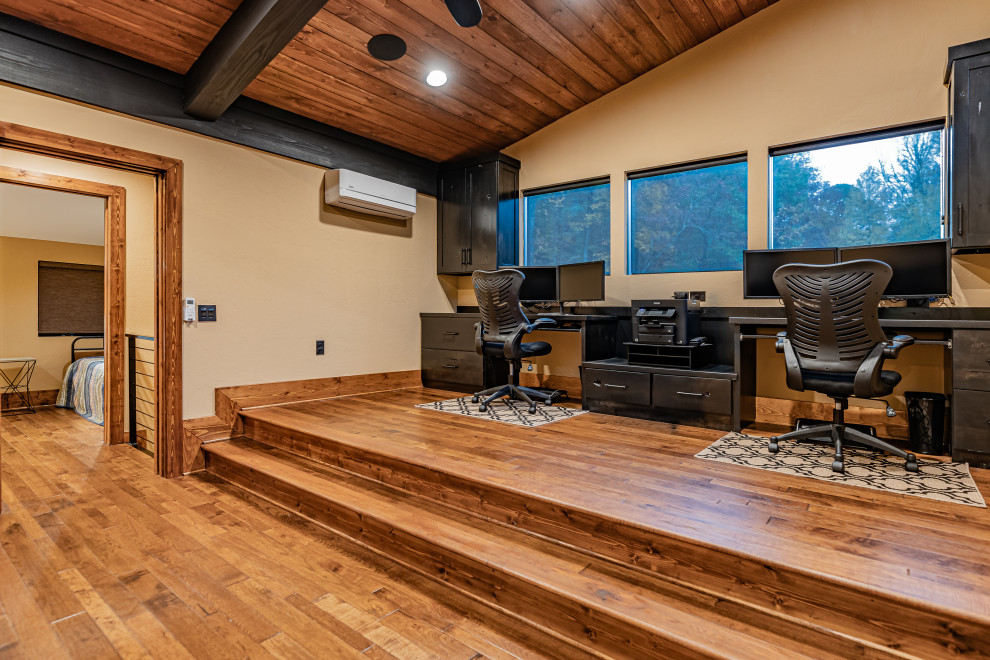 アトランタにあるラグジュアリーな広いラスティックスタイルのおしゃれなホームオフィス・書斎 (ベージュの壁、無垢フローリング、暖炉なし、造り付け机、茶色い床) の写真