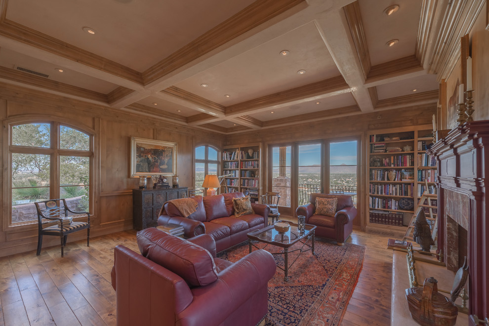 Large mediterranean home office in Phoenix with a reading nook, brown walls, medium hardwood flooring, a standard fireplace and a stone fireplace surround.