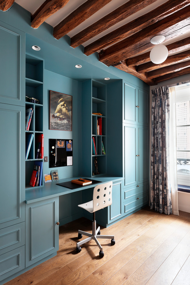 This is an example of an eclectic home office in London with medium hardwood flooring, a built-in desk and brown floors.