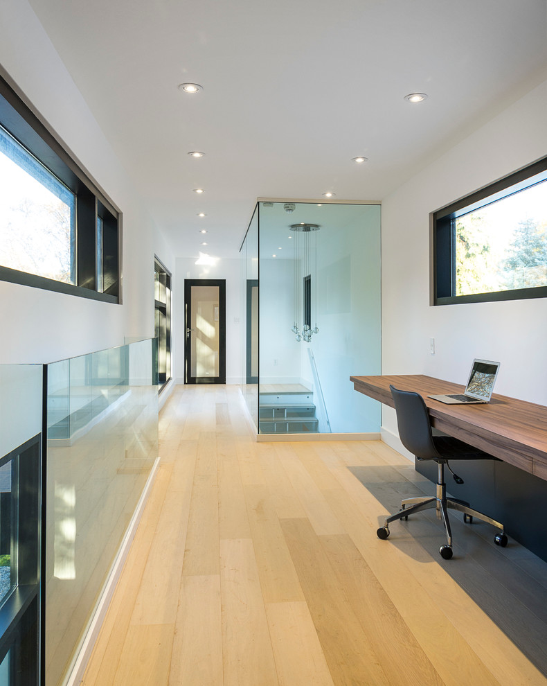 Cette image montre un grand bureau minimaliste avec un mur blanc, parquet clair, aucune cheminée et un bureau intégré.