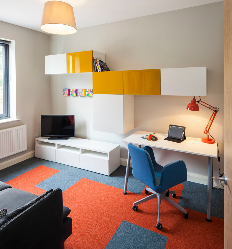 Mittelgroßes Modernes Arbeitszimmer mit Arbeitsplatz, grauer Wandfarbe, Teppichboden, freistehendem Schreibtisch und buntem Boden in Dublin