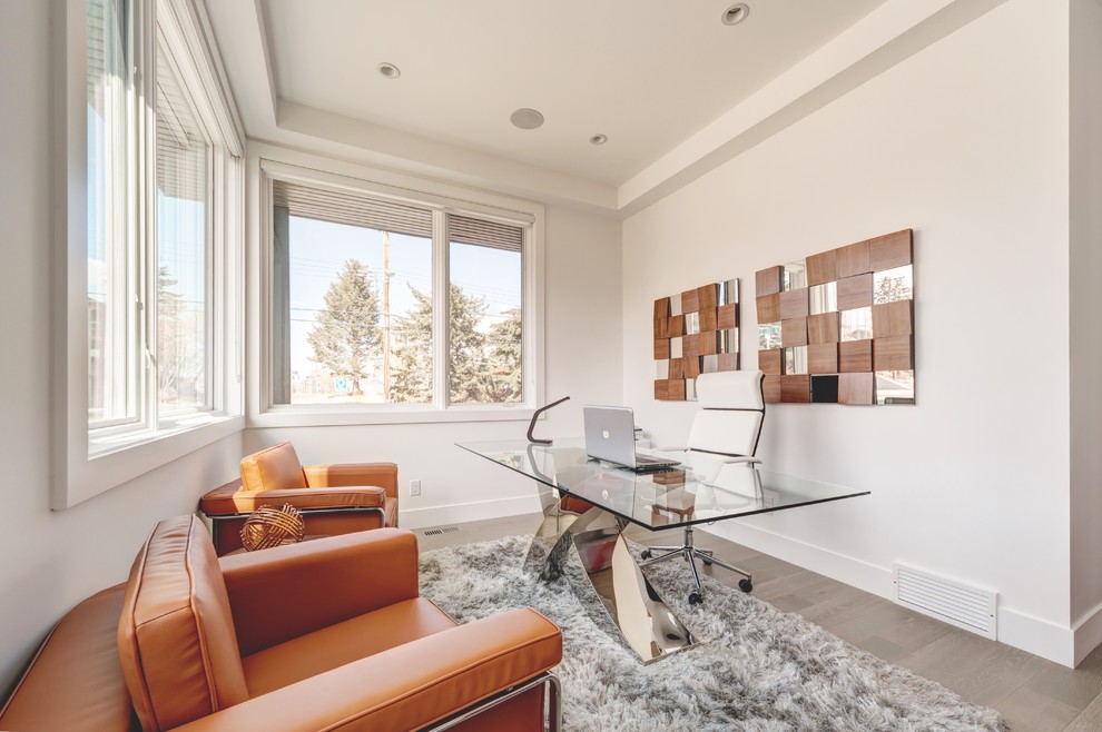 Imagen de despacho actual de tamaño medio con paredes beige, suelo de madera clara y escritorio independiente