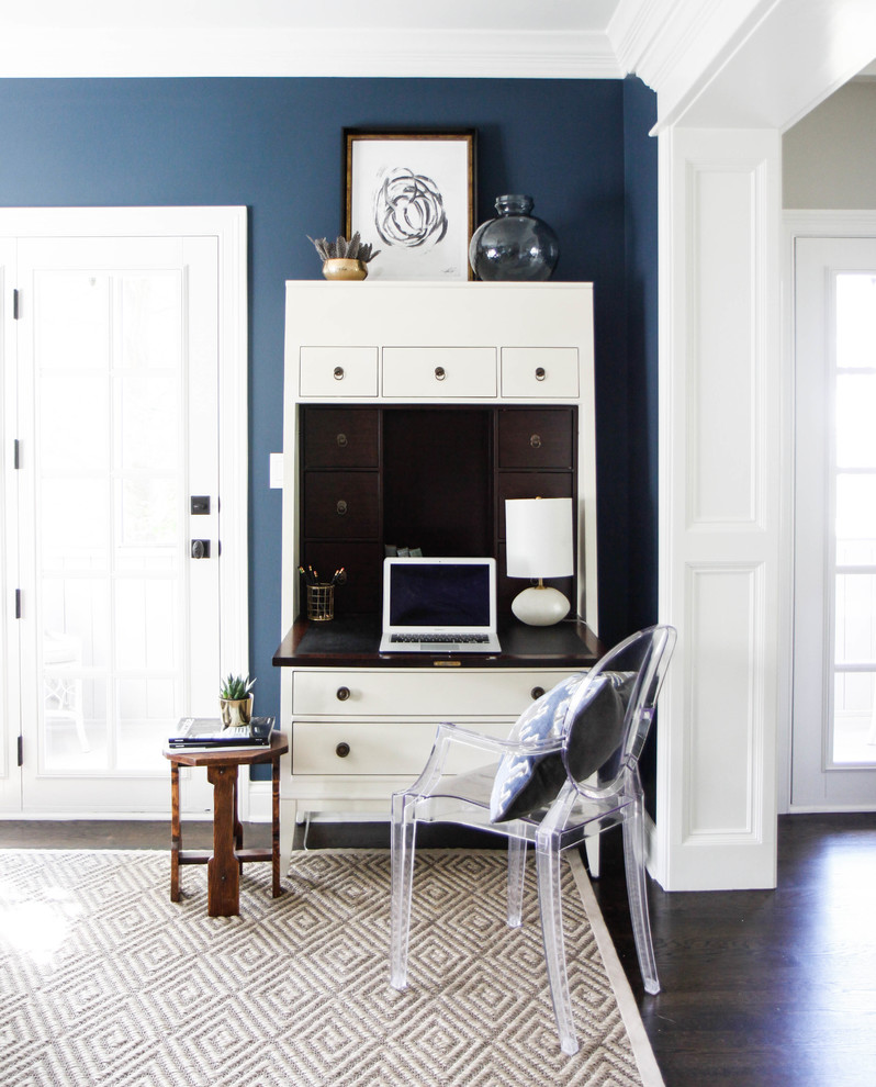 Inredning av ett klassiskt mellanstort arbetsrum, med blå väggar, mörkt trägolv och ett fristående skrivbord