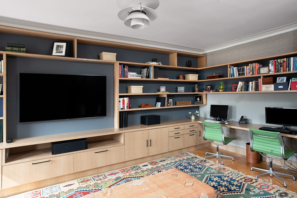 Modern inredning av ett mellanstort hemmabibliotek, med grå väggar, ett inbyggt skrivbord, mellanmörkt trägolv och brunt golv