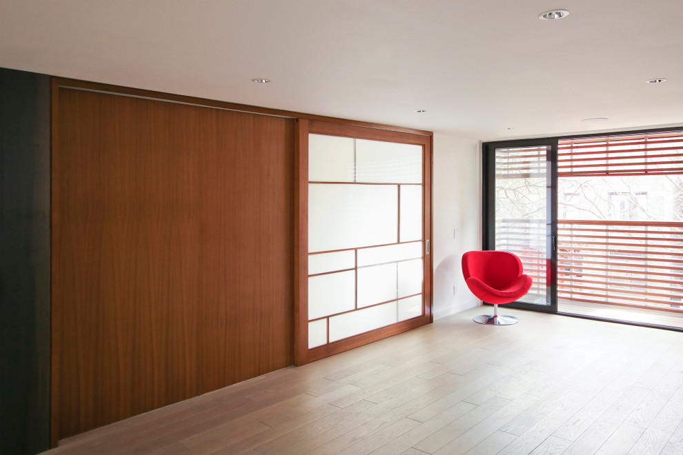 Mittelgroßes Modernes Arbeitszimmer mit Arbeitsplatz, weißer Wandfarbe, hellem Holzboden und Einbau-Schreibtisch in New York