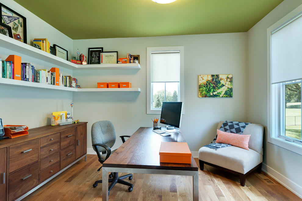 Diseño de despacho actual con suelo de madera en tonos medios y escritorio independiente