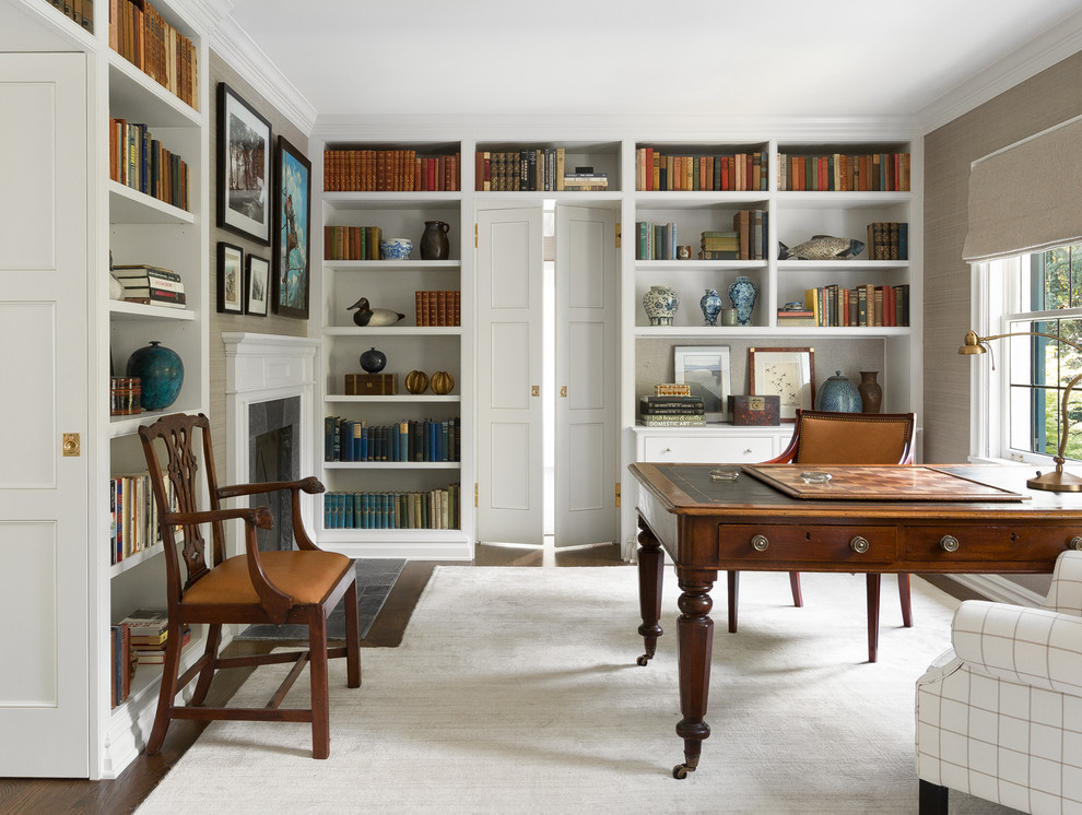 Источник вдохновения для домашнего уюта: домашняя библиотека в классическом стиле с стандартным камином и отдельно стоящим рабочим столом