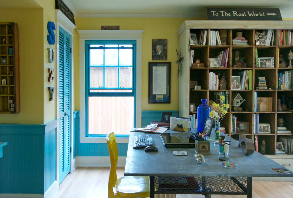 Shabby chic-inspirerad inredning av ett mellanstort hemmabibliotek, med gula väggar, ljust trägolv och ett fristående skrivbord