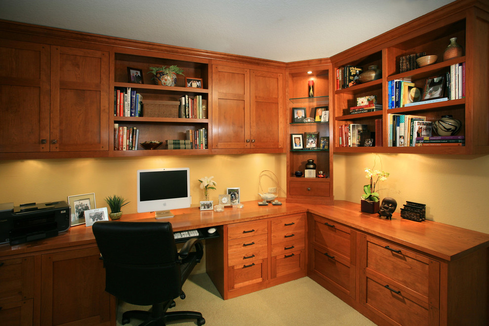 Diseño de despacho de estilo americano grande con paredes amarillas, moqueta y escritorio empotrado