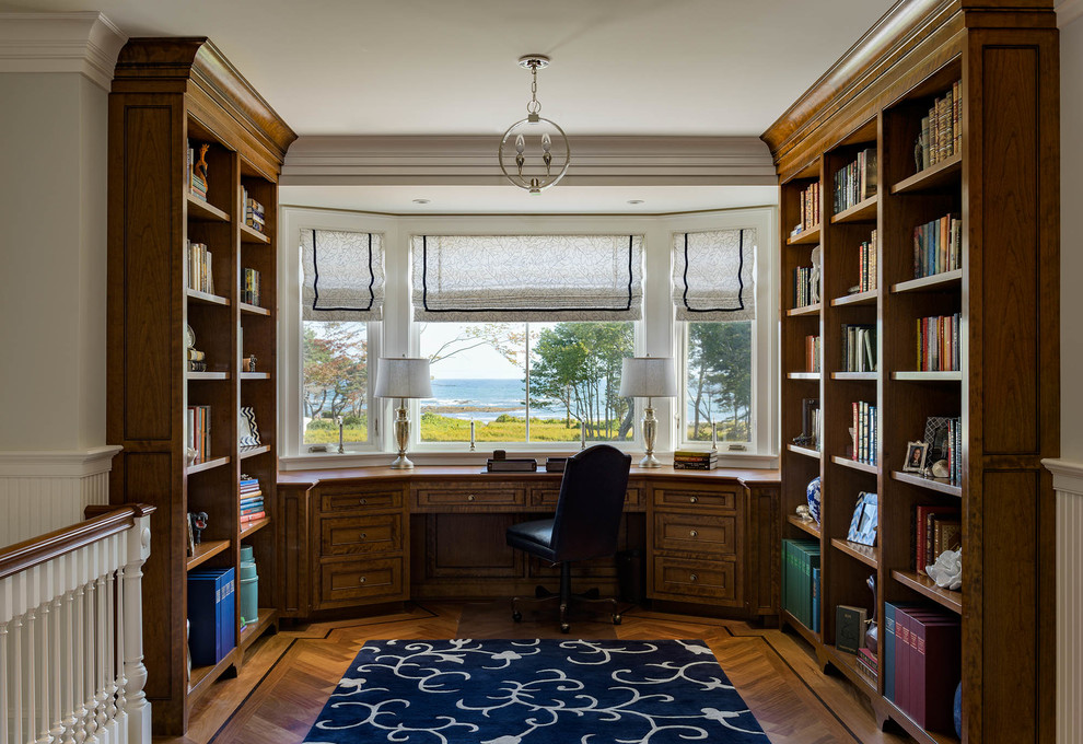 На фото: домашняя библиотека в классическом стиле с паркетным полом среднего тона, встроенным рабочим столом и коричневым полом с