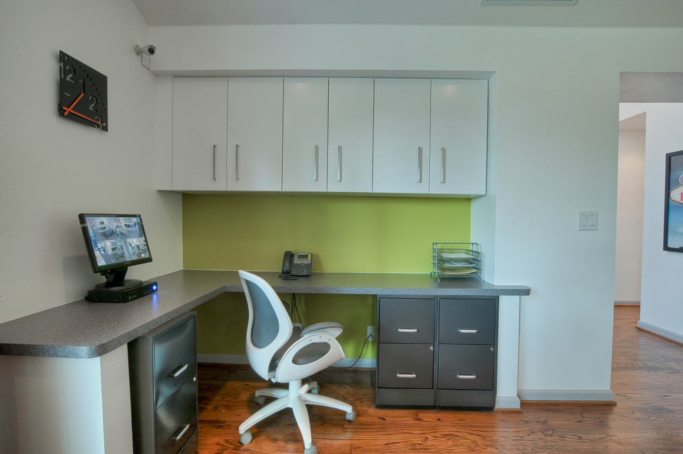 Small mid-century modern built-in desk medium tone wood floor home office photo in Dallas with green walls