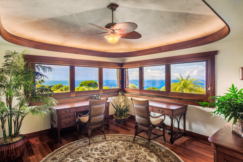 Mittelgroßes Arbeitszimmer mit Arbeitsplatz, beiger Wandfarbe, braunem Holzboden und freistehendem Schreibtisch in Hawaii