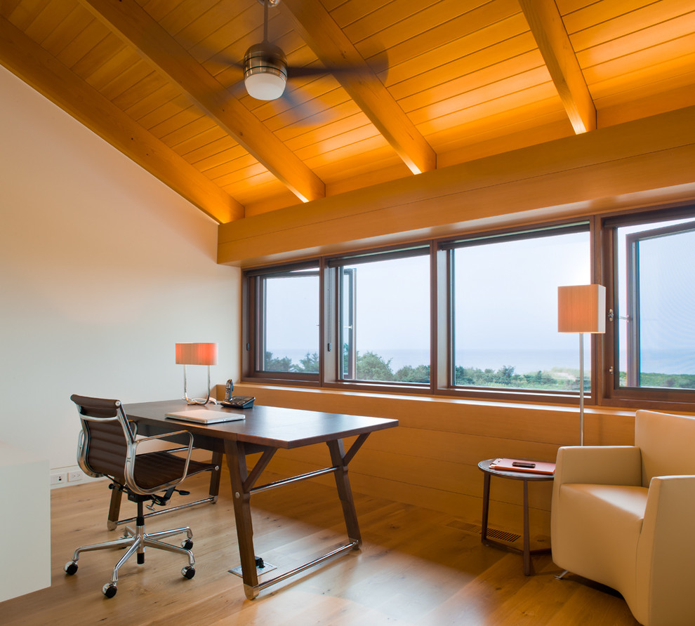 Aménagement d'un bureau contemporain avec un mur blanc, un sol en bois brun et un bureau indépendant.
