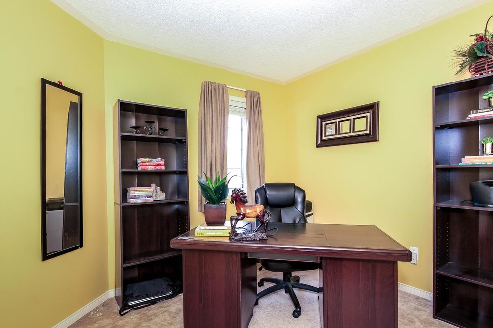 На фото: домашняя мастерская среднего размера в стиле неоклассика (современная классика) с желтыми стенами, ковровым покрытием и отдельно стоящим рабочим столом без камина с