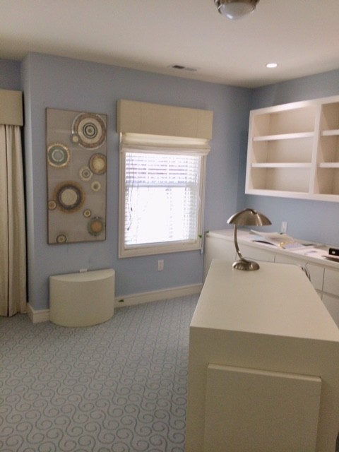 Bild på ett stort funkis arbetsrum, med ett bibliotek, blå väggar, heltäckningsmatta, en dubbelsidig öppen spis, en spiselkrans i sten, ett fristående skrivbord och blått golv