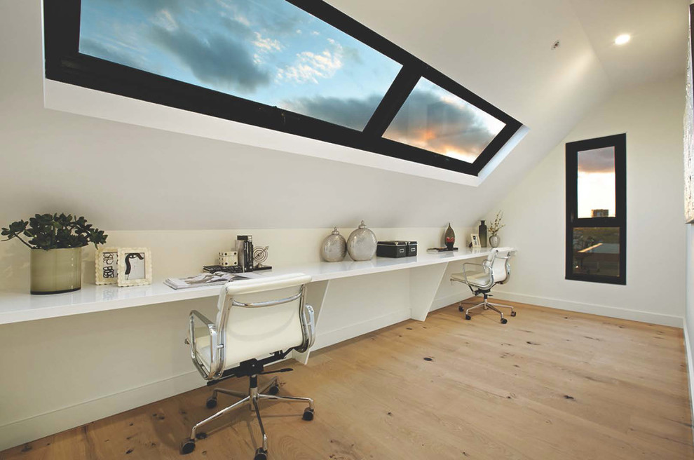Aménagement d'un bureau contemporain avec un mur blanc, un sol en bois brun et un bureau intégré.