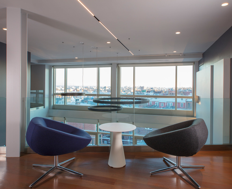Diseño de despacho moderno grande con paredes grises, suelo de madera en tonos medios y escritorio independiente