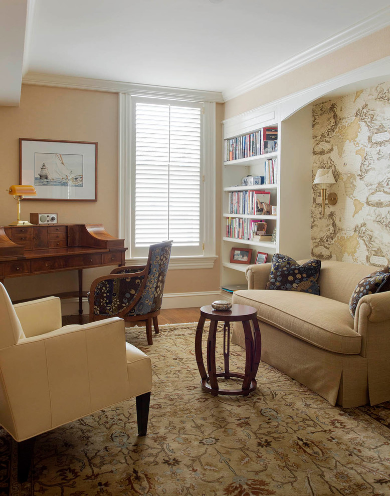 Exempel på ett klassiskt hemmabibliotek, med beige väggar, mellanmörkt trägolv, ett fristående skrivbord och beiget golv
