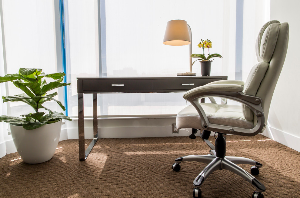 Cette image montre un petit bureau minimaliste avec un mur gris, moquette, un bureau indépendant et un sol marron.