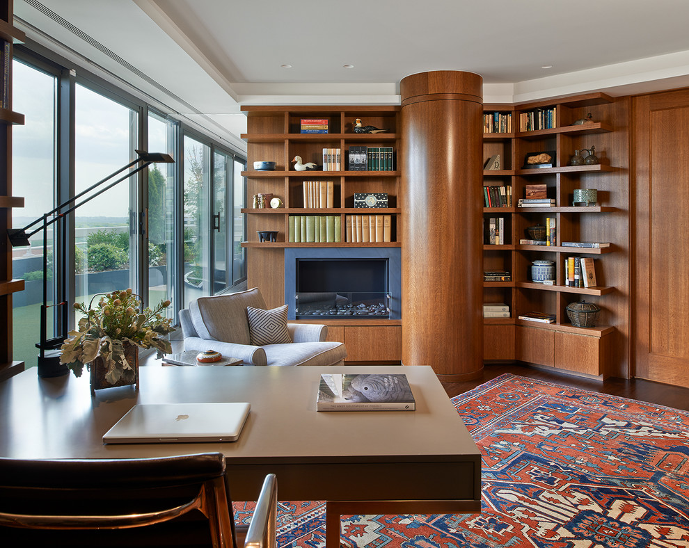 Exempel på ett stort modernt hemmabibliotek, med mörkt trägolv, en standard öppen spis, ett fristående skrivbord, bruna väggar, en spiselkrans i metall och brunt golv