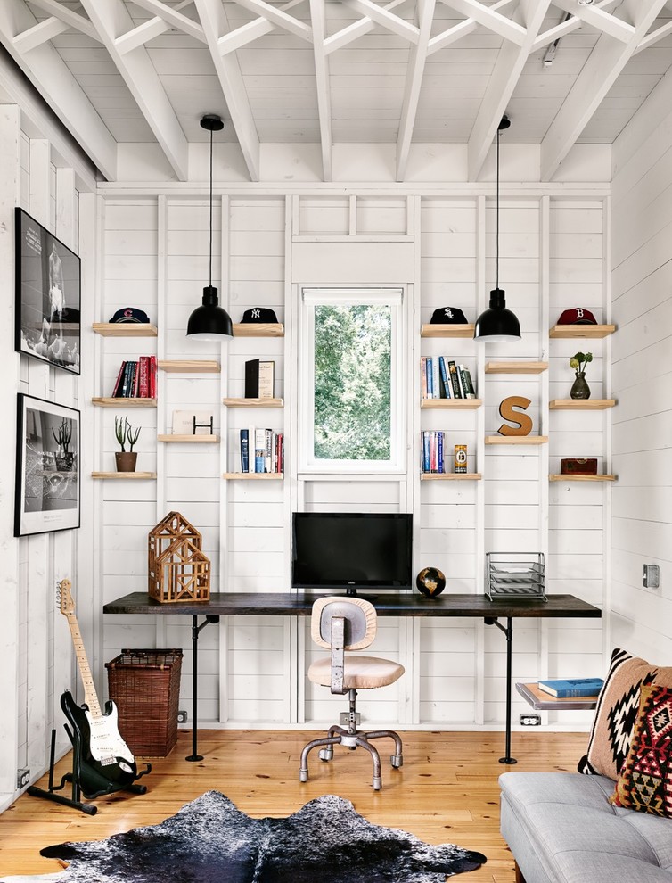 Mid-sized farmhouse built-in desk light wood floor study room photo in Austin with white walls