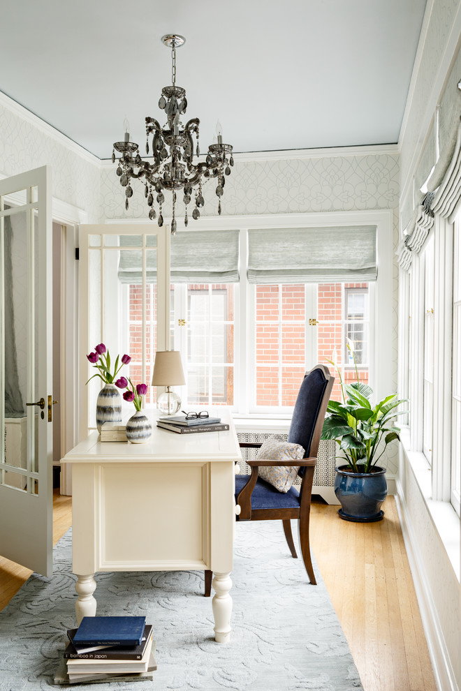 Ejemplo de despacho tradicional de tamaño medio con paredes blancas, suelo de madera clara y escritorio independiente