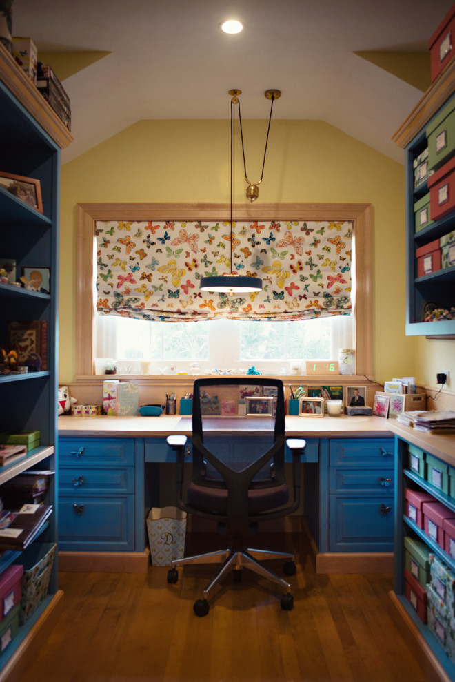Eklektisk inredning av ett litet hobbyrum, med gula väggar, ljust trägolv och ett inbyggt skrivbord