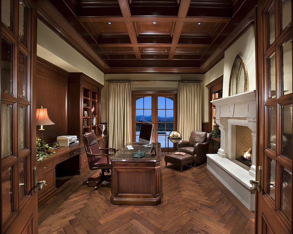 Ejemplo de despacho tradicional con paredes beige, suelo de madera oscura, todas las chimeneas y escritorio independiente