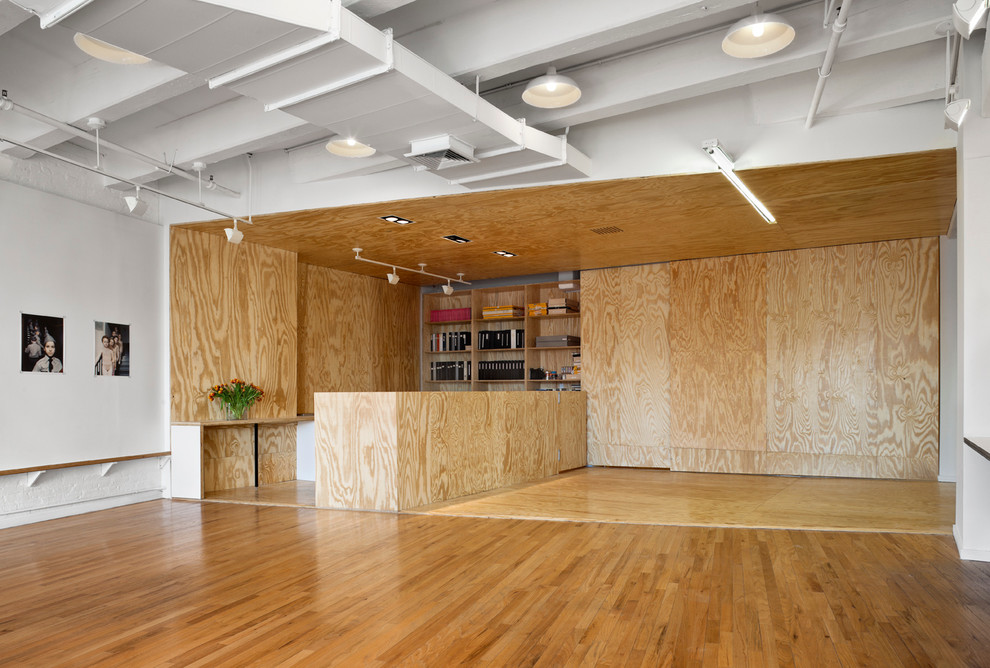Industrial Arbeitszimmer mit Studio, weißer Wandfarbe und braunem Holzboden in New York