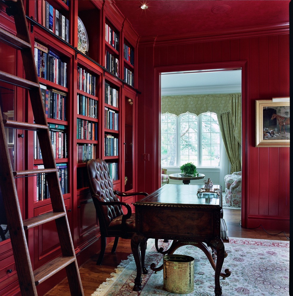 Inspiration för klassiska arbetsrum, med röda väggar, mellanmörkt trägolv, ett fristående skrivbord och brunt golv