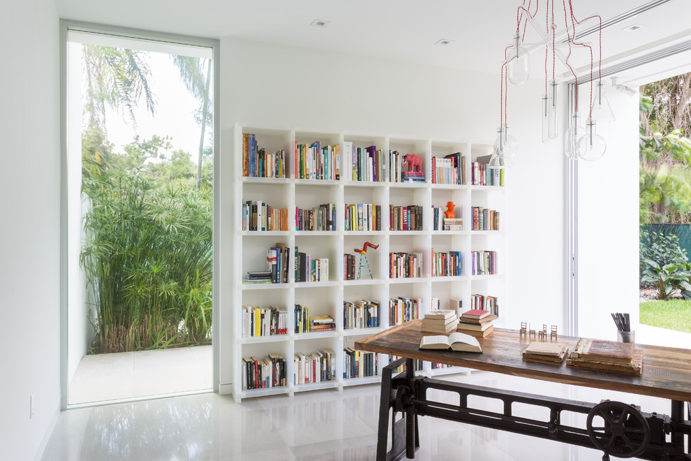 Esempio di uno studio minimal con libreria, pareti bianche, scrivania autoportante e pavimento bianco