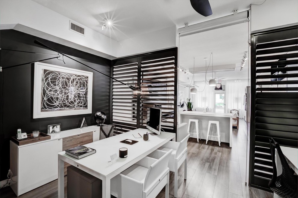 Trendy freestanding desk medium tone wood floor study room photo in Other with black walls