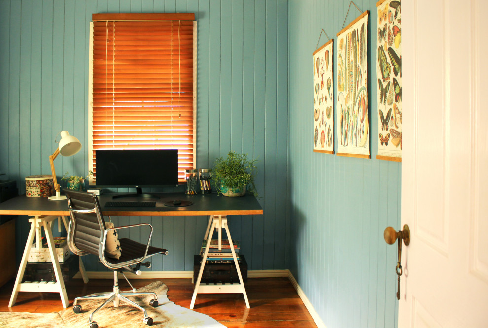 Ejemplo de despacho ecléctico de tamaño medio con paredes azules, suelo de madera en tonos medios y escritorio independiente