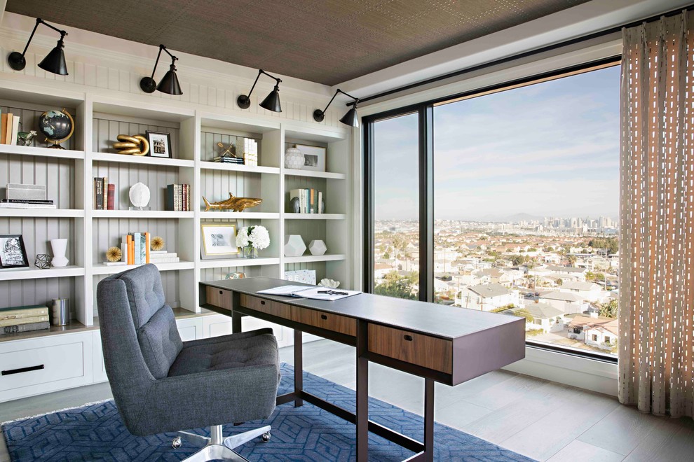 Modelo de despacho clásico renovado con paredes blancas, suelo de madera en tonos medios, escritorio independiente y suelo gris