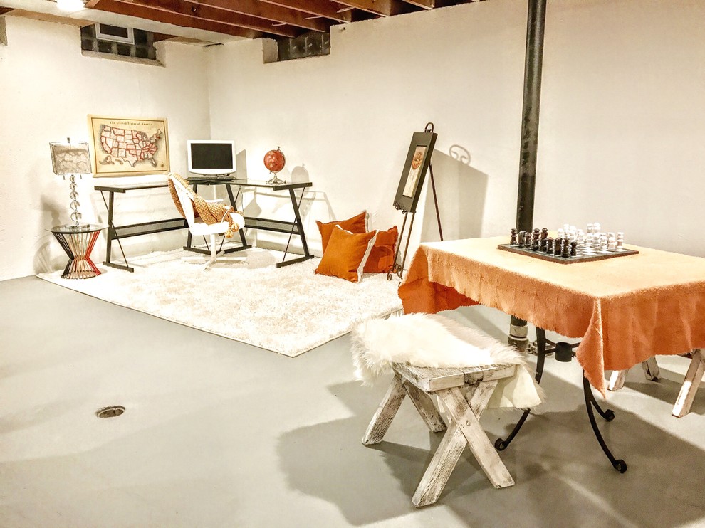 Modelo de estudio contemporáneo grande sin chimenea con paredes beige, suelo de cemento, escritorio independiente y suelo gris