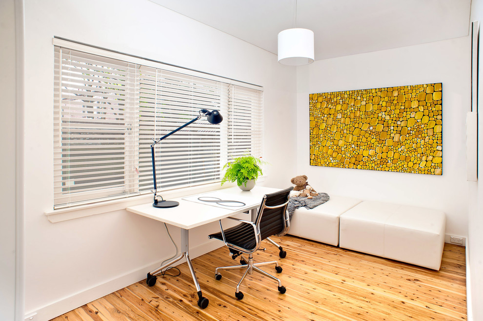 Ejemplo de despacho actual pequeño sin chimenea con paredes blancas, suelo de madera clara y escritorio independiente