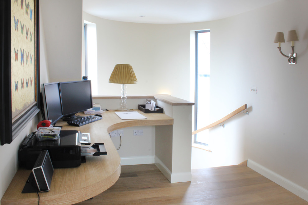 Ejemplo de despacho contemporáneo pequeño con paredes blancas, suelo de madera en tonos medios y escritorio empotrado