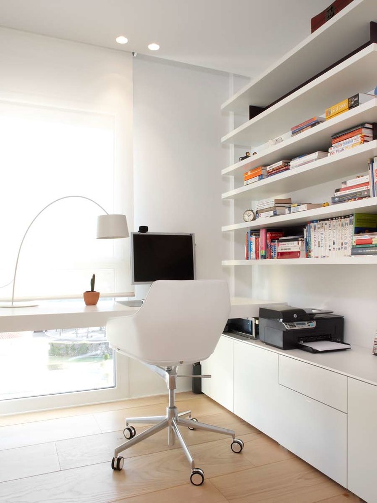 Inspiration för ett litet funkis hemmabibliotek, med vita väggar, ljust trägolv och ett inbyggt skrivbord