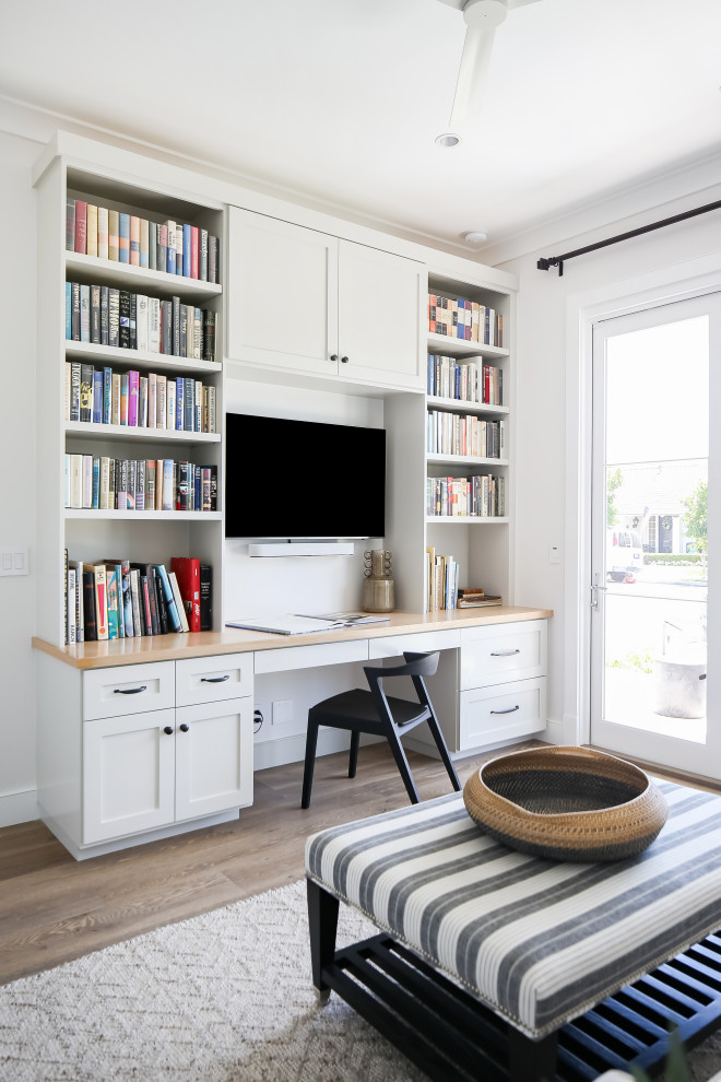 Mittelgroßes Klassisches Arbeitszimmer ohne Kamin mit weißer Wandfarbe, braunem Holzboden, Einbau-Schreibtisch und braunem Boden in Orange County