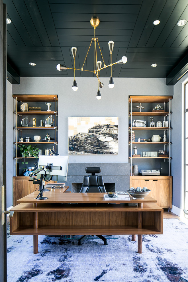 Foto di un ufficio minimal con pareti grigie, moquette, camino classico, cornice del camino in pietra, scrivania autoportante e pavimento viola