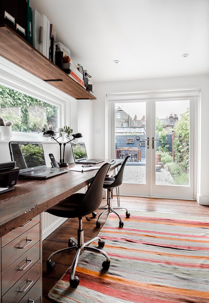 Immagine di un piccolo ufficio industriale con pareti bianche, parquet scuro, scrivania autoportante e pavimento marrone