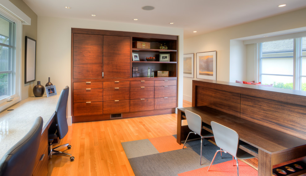 Immagine di un ufficio moderno di medie dimensioni con pareti beige, pavimento in legno massello medio, scrivania incassata e pavimento marrone
