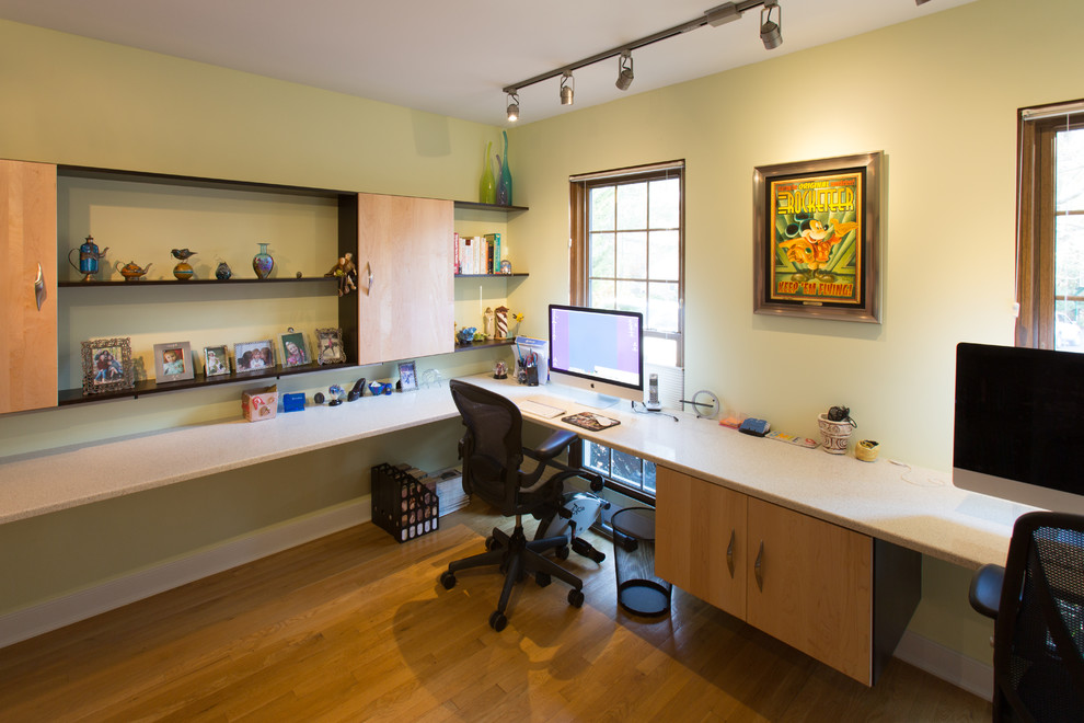 Example of a mid-sized minimalist built-in desk medium tone wood floor study room design in DC Metro with green walls